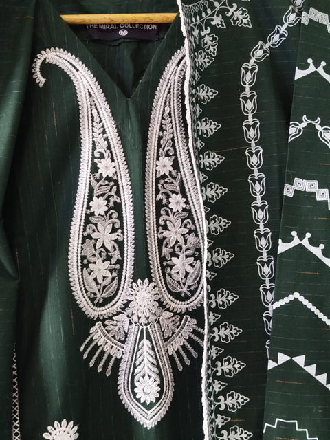 Green garment with intricate white embroidery on a matching fabric background