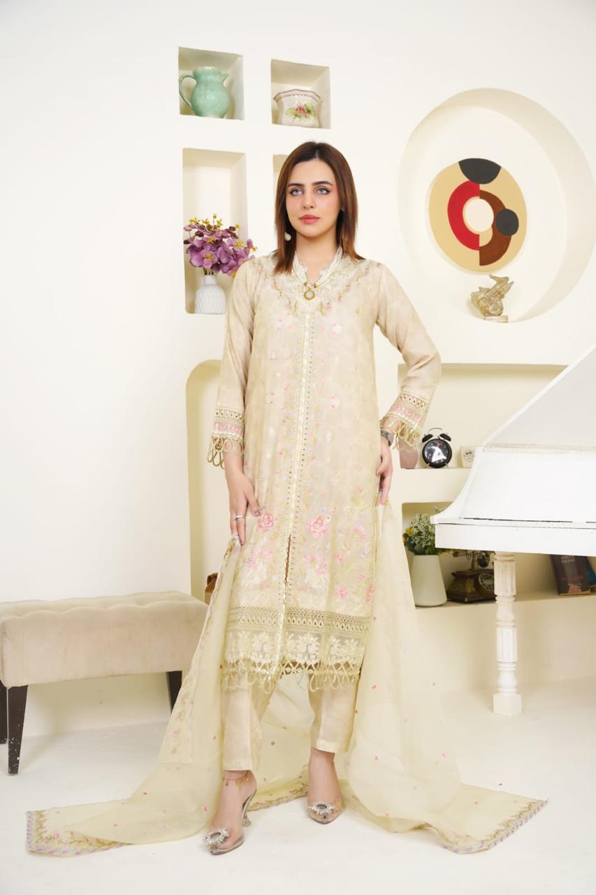 Woman in a cream embroidered outfit standing in a stylish room with decor elements.