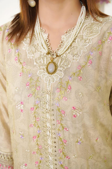 Close-up of a person wearing a beige embroidered blouse with floral patterns and a pearl necklace.